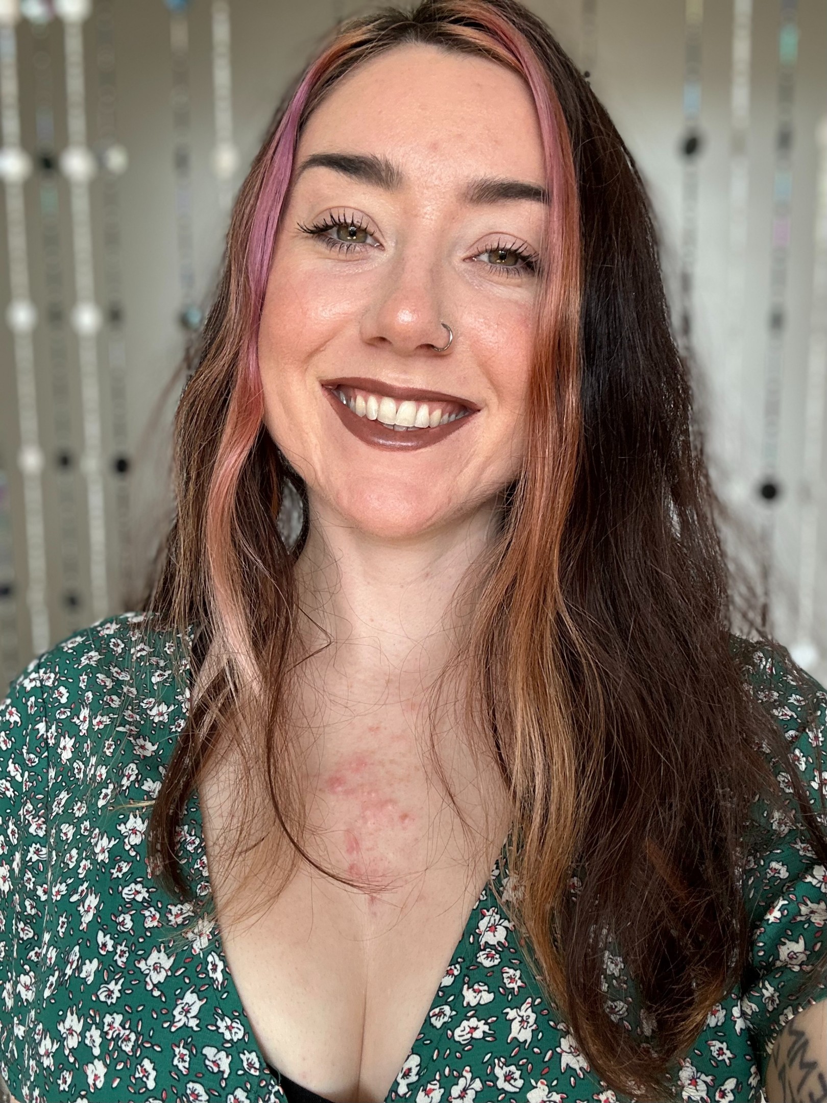 A headshot of Emily, a white woman with long brown hair, wearing a green top.