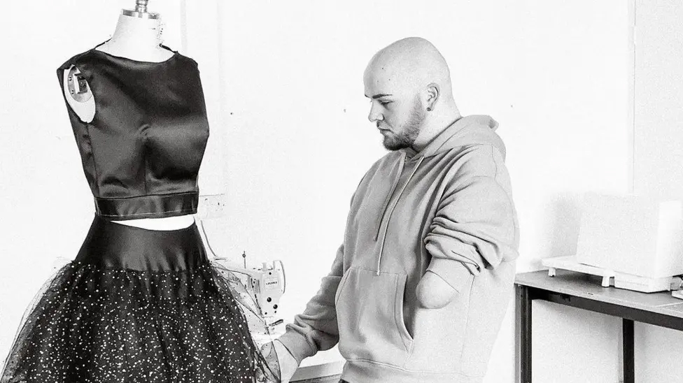 Ryan Rix focuses on a skirt that he is working on.