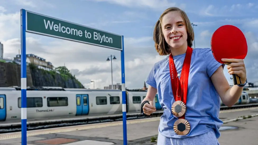 The Paralympian Bly Twomey shows her medals in front of the new Brighton Station sign, renamed to 'Blyton Station.'