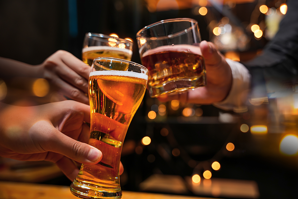 A group of people clink glasses of alcoholic drinks together.